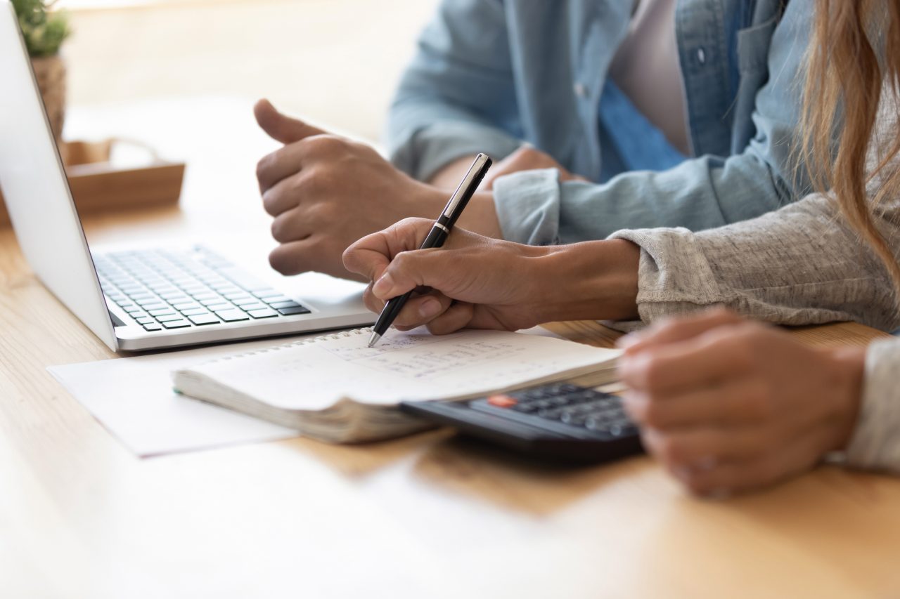 Close up spouses working out mortgage payments using laptop